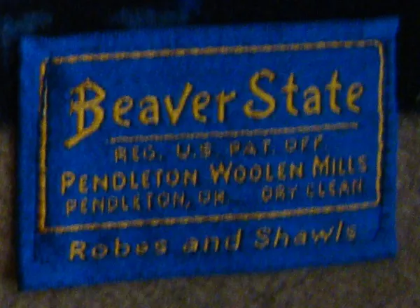 A blue Beaver State blanket label with yellow lettering: "Beaver State, Reg. U.S. Pat. Off., Pendleton Woolen Mills, Pendleton, Or., Dry Clean, Robes and Shawls".